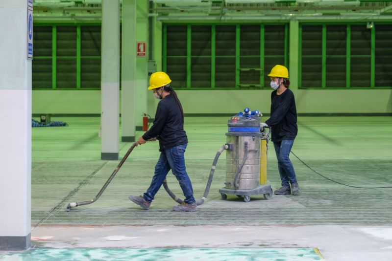 two workers installing epoxy floor in an underground garage